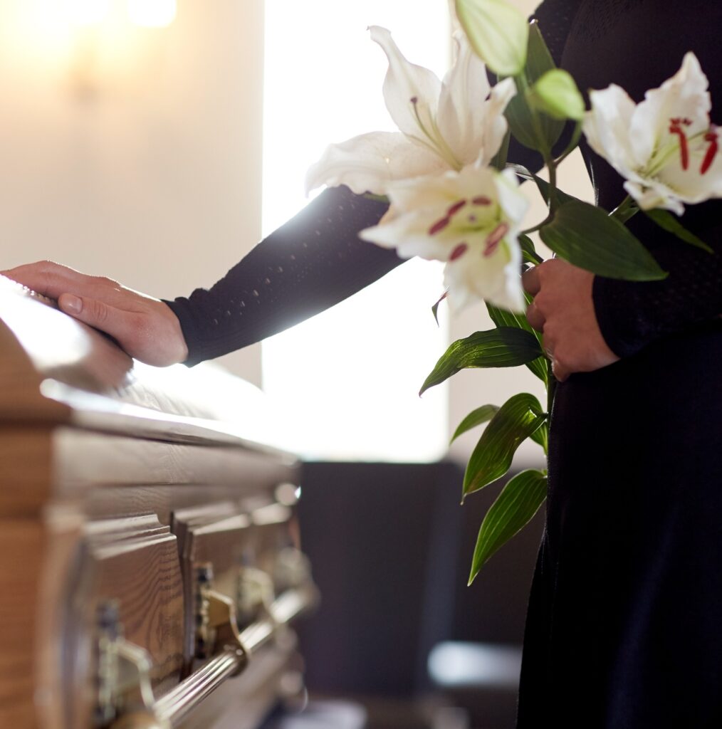 woman with lily flowers and coffin at funeral